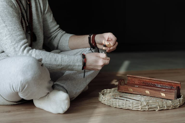 A person lighting palo santo incense, invoking calm and spirituality indoors.